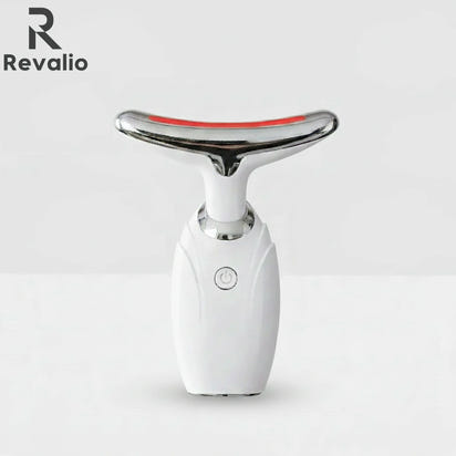 Front view of the white Revalio LED Facial Neck Massager standing upright against a white and grey background.