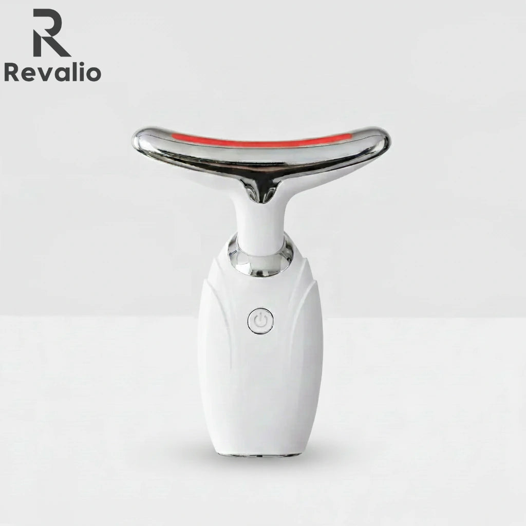 Front view of the white Revalio LED Facial Neck Massager standing upright against a white and grey background.