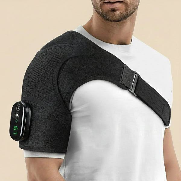 Man wearing the Revalio Heated Shoulder Massager Brace over a white T shirt showing adjustable strap and digital controller on his upper arm.