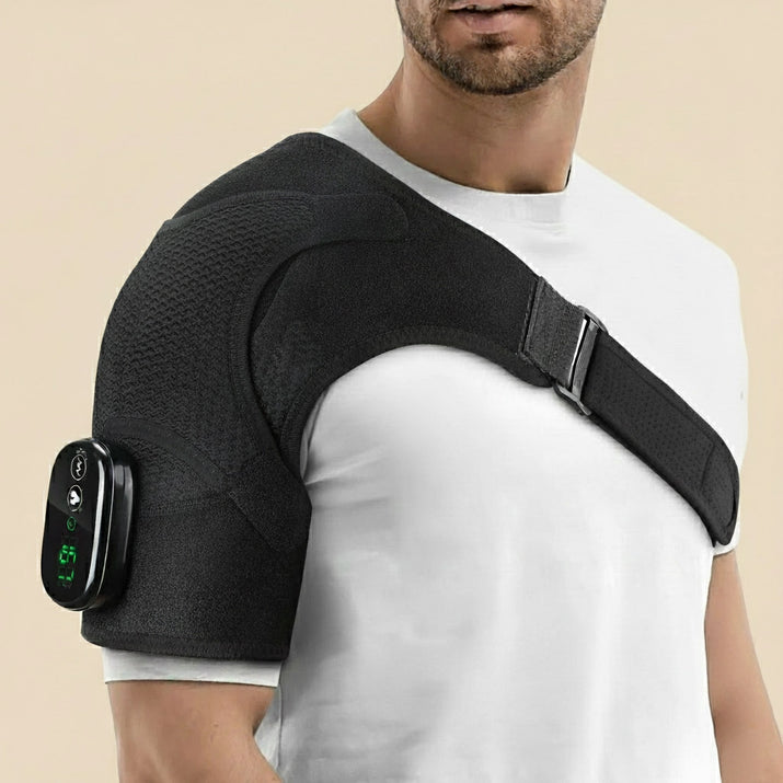 Man wearing the Revalio Heated Shoulder Massager Brace over a white T shirt showing adjustable strap and digital controller on his upper arm.
